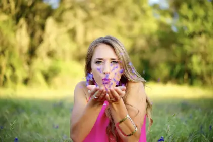 Frau bläst Blütenblätter aus den Händen