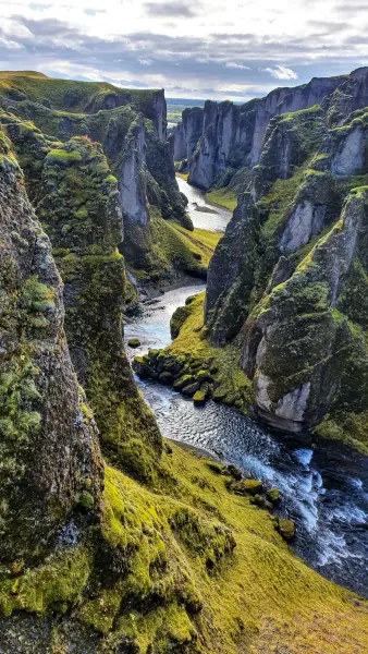 Grüner und grauer, felsiger Berg am Fluss